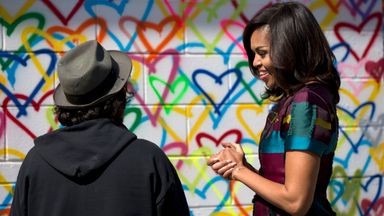 First lady Michelle Obama looks to artist Mr. Brainwash during a live painting of a Let Girls Learn mural at Union Market in Washington, Tuesday, March 8, 2016. Pic: AP